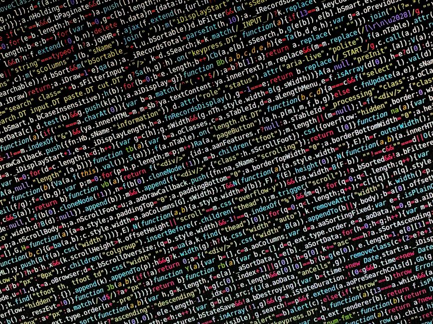 Close-up view of a computer screen displaying a dense overlay of colorful code with various programming syntax, including tags, brackets, and keywords, set against a dark background. The intricate dig