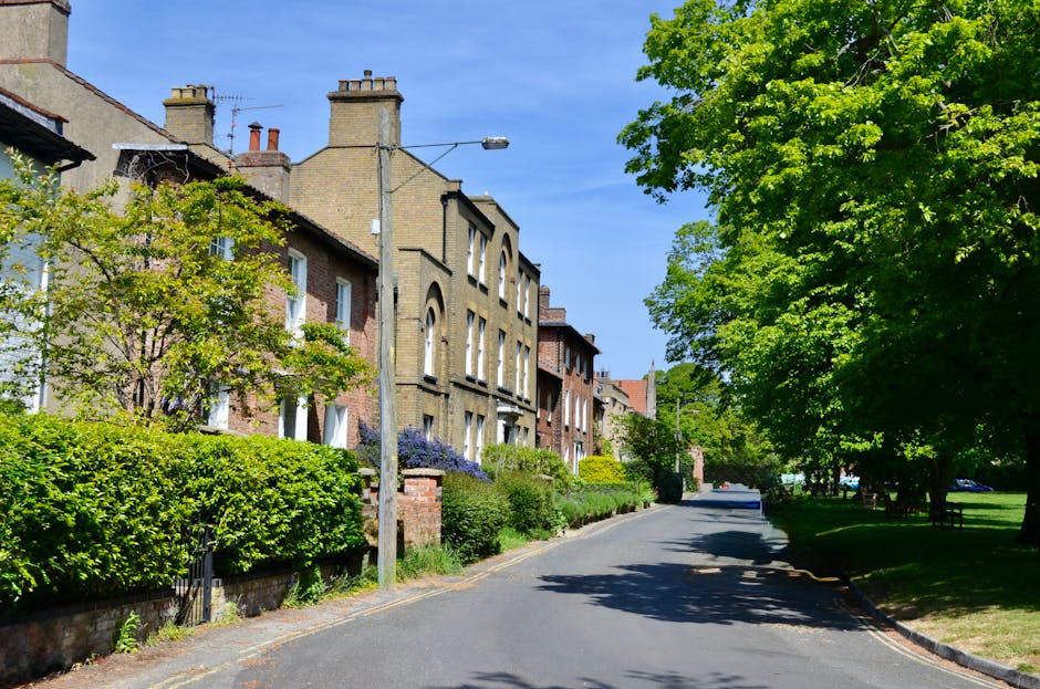 A modern residential estate featuring multiple multi-storey apartment buildings with balconies, constructed from materials including wood, glass, and concrete. The buildings are arranged around a land